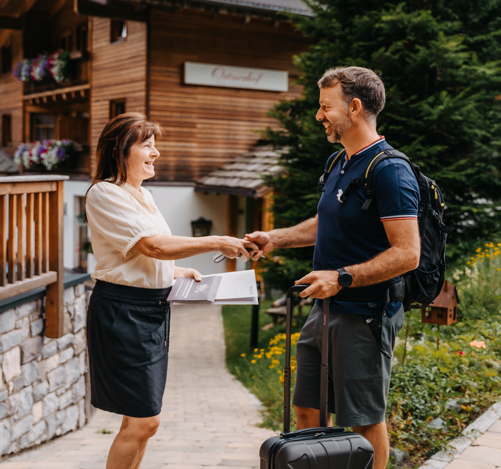 Gastgeberin begrüßt einen Gast, der gerade vorm Hotel ankommt - Hotel Ortnerhof