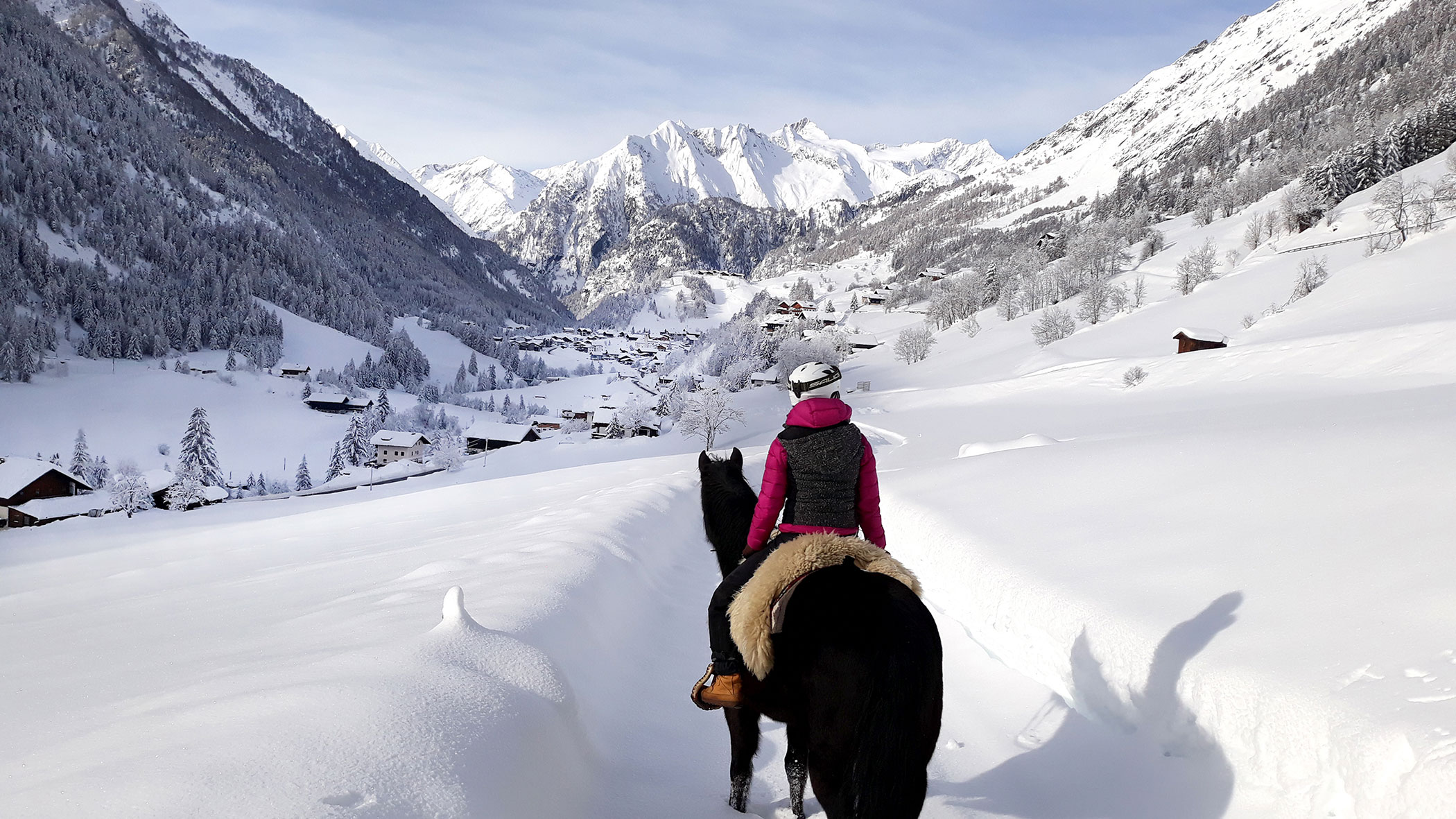 Eine Frau reitet durch die tief verschneite Winterlandschaft in Prägraten - Hotel Ortnerhof.