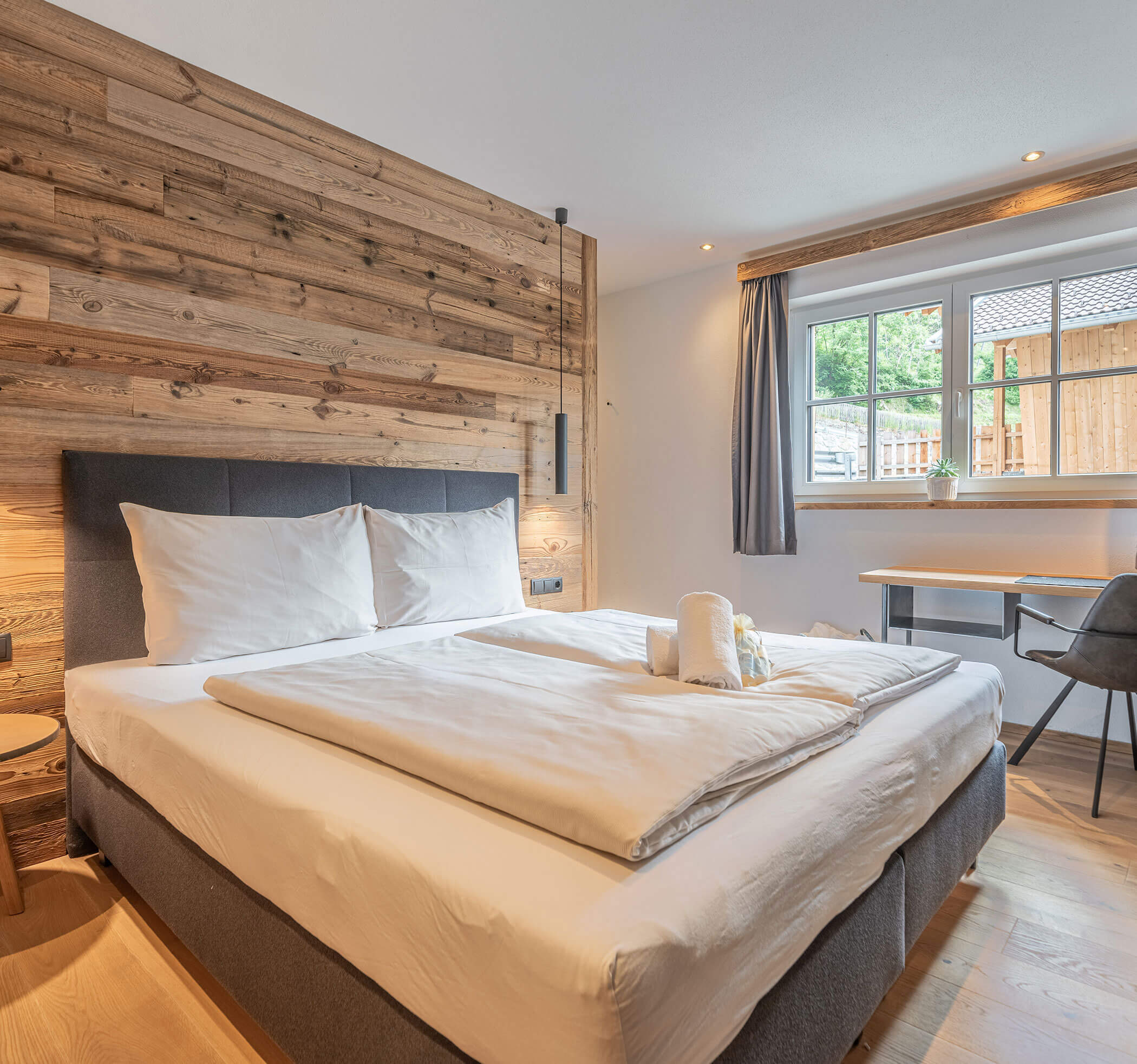 Doppelbett mit Handtüchern und Holzwand - Hotel Ortnerhof