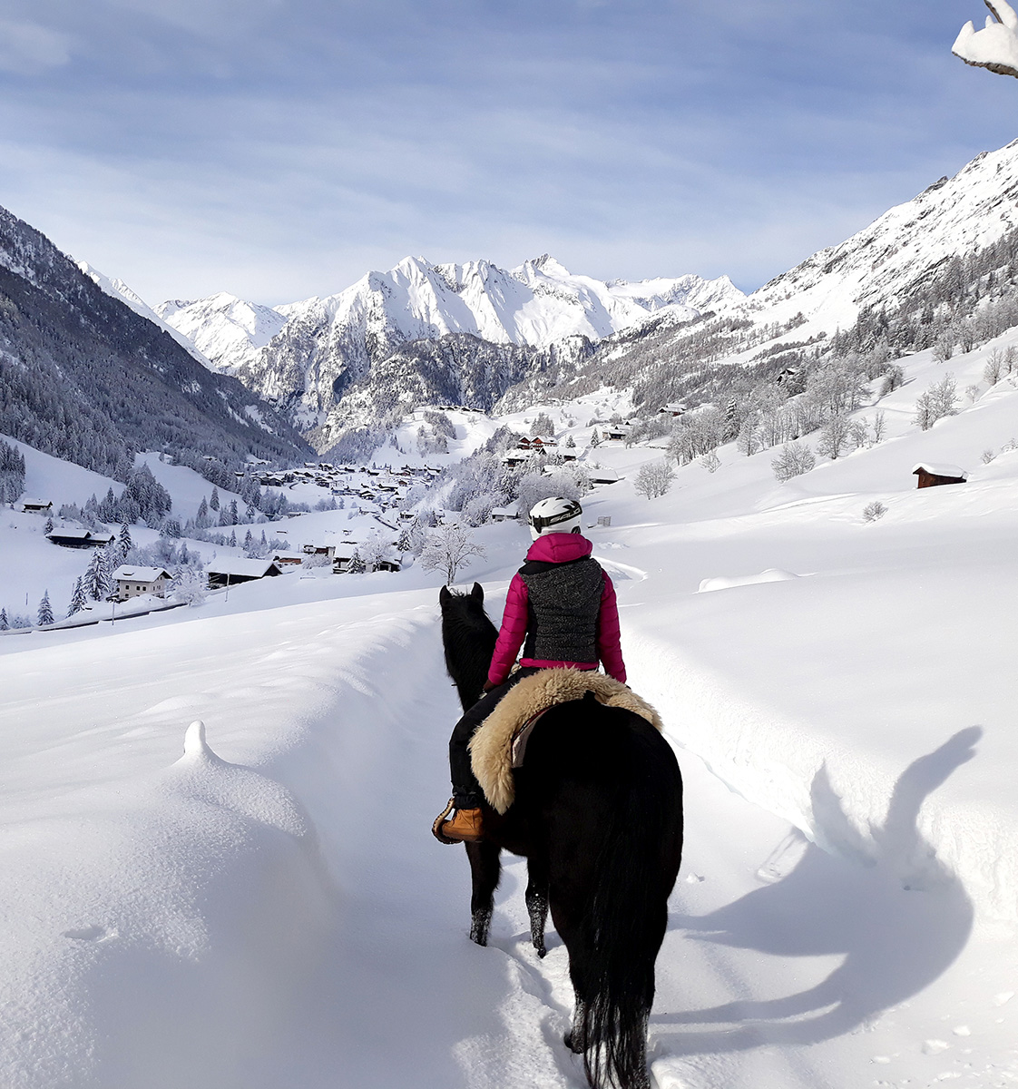 Eine Frei reitet durch die tief verschneite Winterlandschaft in Prägraten - Hotel Ortnerhof.